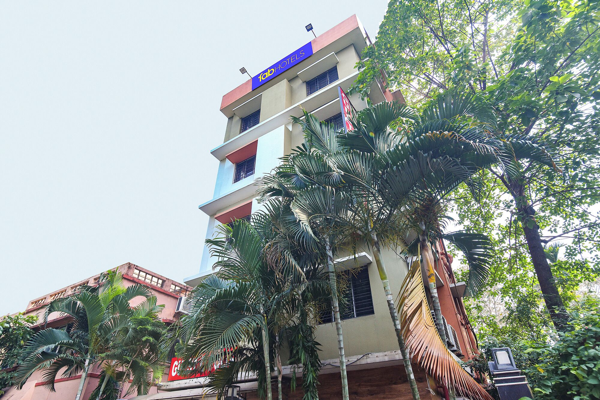 A multi-story hotel with balconies, surrounded by palm trees.