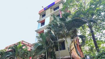 A multi-story hotel with balconies, surrounded by palm trees.