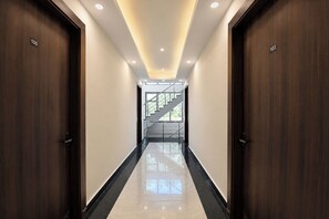 A hallway with wooden doors numbered 106 and 103, leading to a staircase. - Fabhotel Durga Luxury Studio (Gurugram)