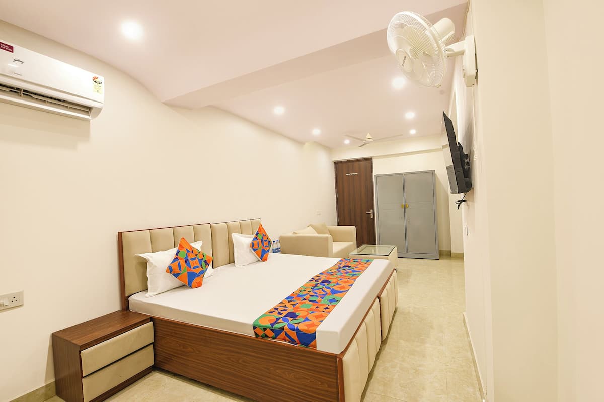 A hotel room with a bed, bedside tables, a TV, a wardrobe, and a ceiling fan.