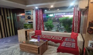 Una sala de estar con un sofá, una mesa de centro, un acuario y vistas a la calle.