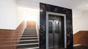 A modern elevator with a marble wall, a staircase with brown steps, and a digital display. - Fabhotel Destiny Living (Pune)