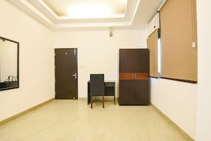 Une pièce comprenant un bureau, une chaise, une armoire et un miroir au mur.