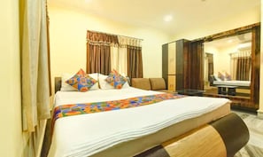 A hotel room with a bed, a desk, a chair, and a mirror. - Fabhotel Rainbow Guest House (Kolkata)