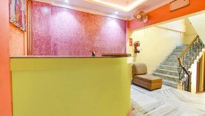 A reception area with a marble floor, a reception desk, a staircase, and a fire extinguisher. - Fabhotel Rainbow Guest House (Kolkata)