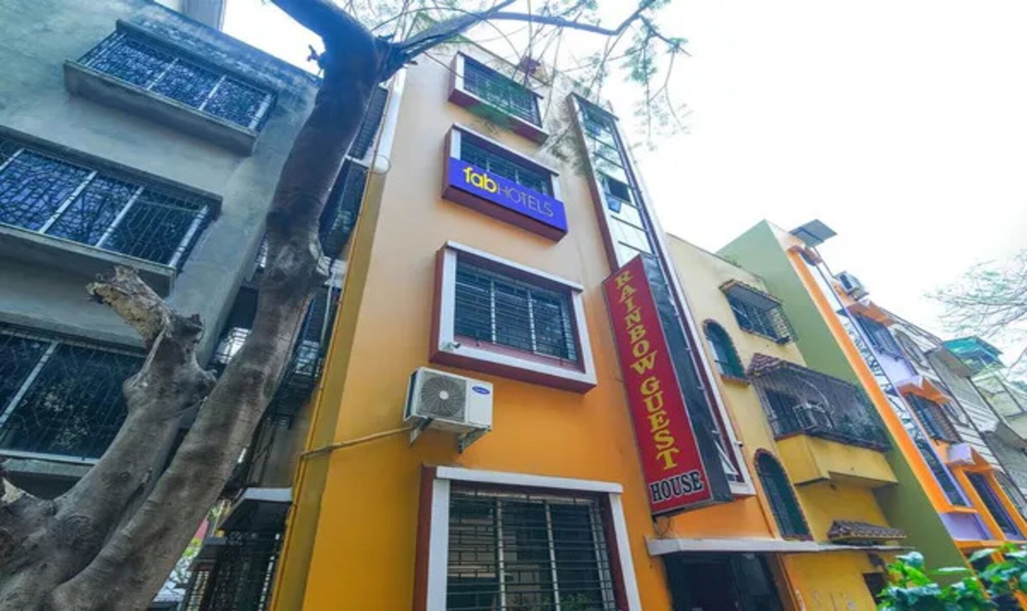 A multi-story building with a sign for 'fab hotels' and a 'Rainbow Guest House' sign.