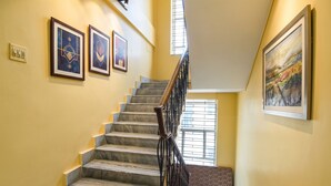 A staircase with marble steps, a black metal railing, and framed artworks on the walls. - Fabhotel Rainbow Guest House (Kolkata)