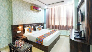 A hotel room with a bed, bedside table, TV, and a ceiling fan. - Fabhotel The Max (Lucknow)