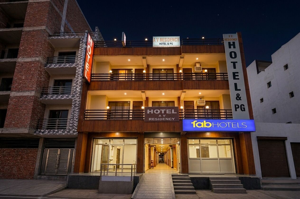 A multi-story hotel with balconies, a sign for 'A V Residency Hotel & PG,' and a 'fabHOTELS' sign.