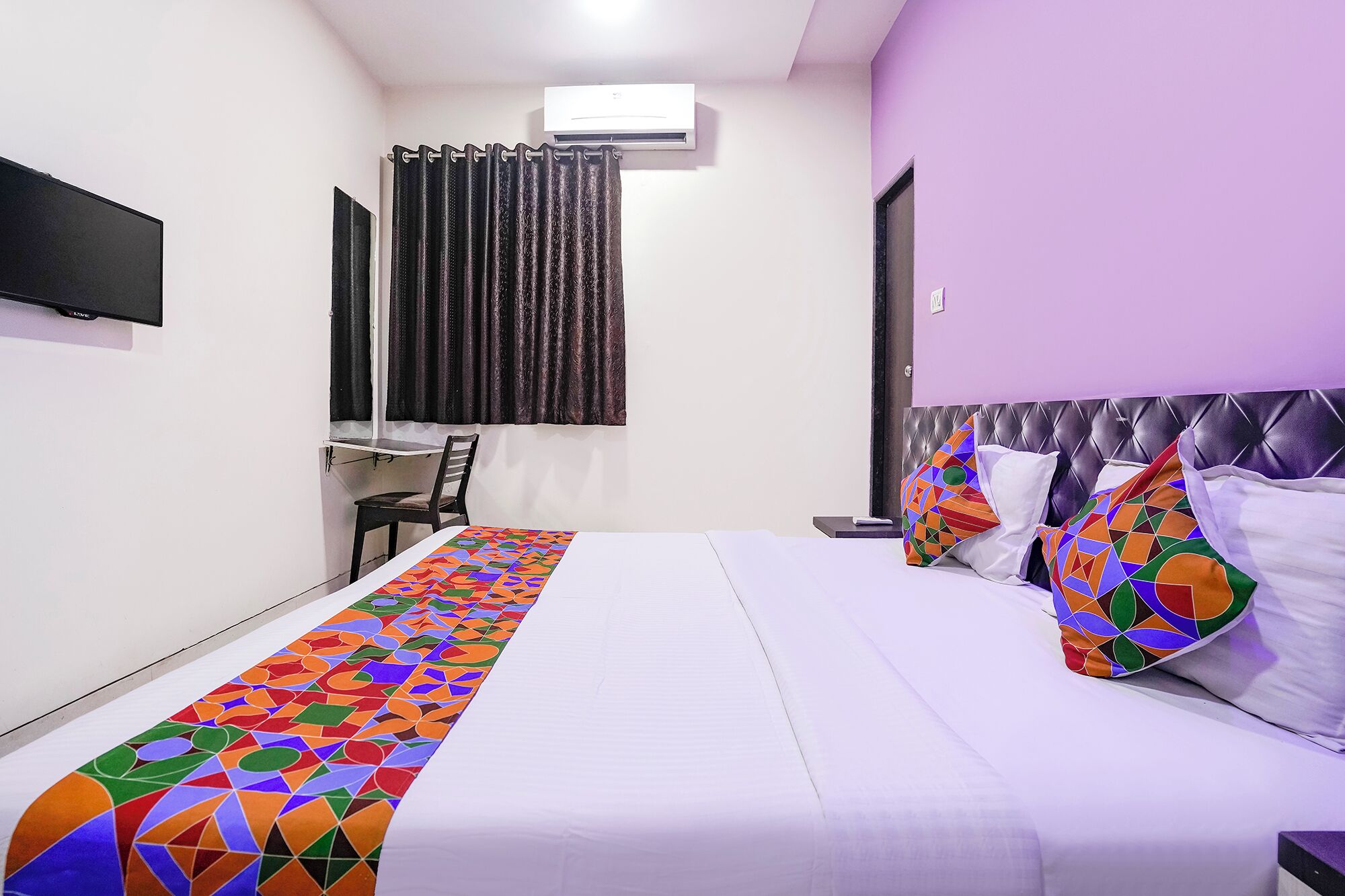 A hotel room with a bed, a desk, and a chair.