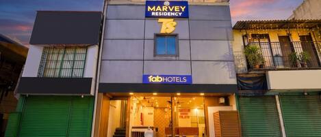 Un immeuble dont la façade porte une enseigne indiquant « Marvey Residency » et « Fab Hotels ».