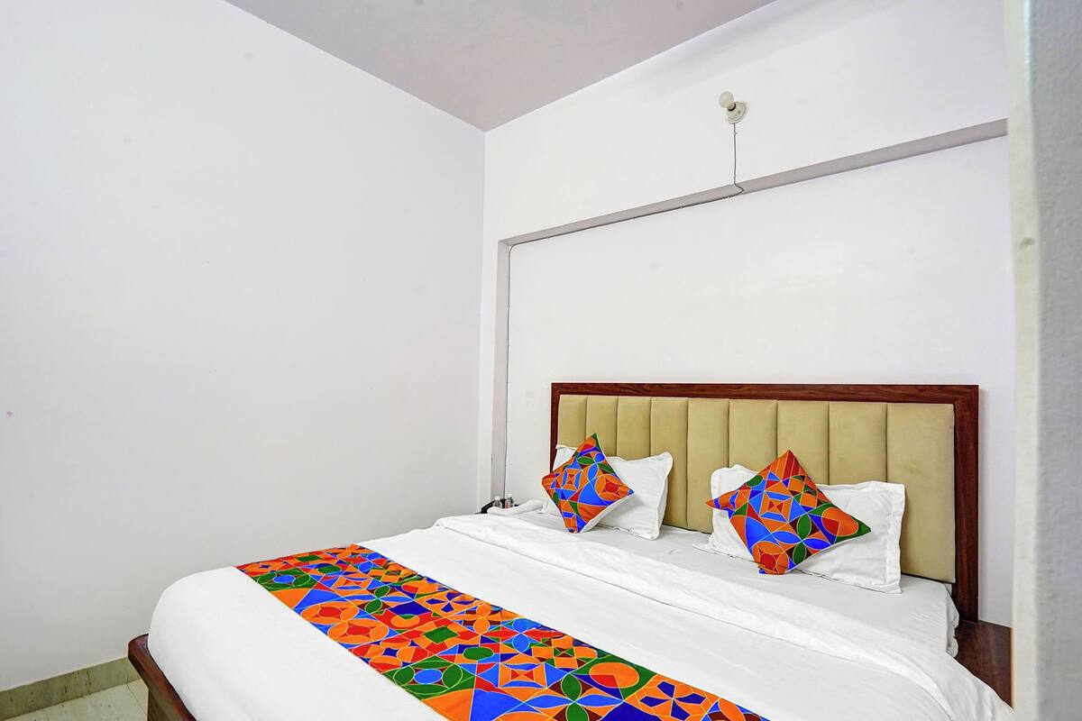 A bed with a white mattress and a colorful geometric-patterned bedspread.