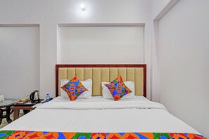 Een hotelkamer met een bed, twee kussens, een nachtkastje en een stoel.