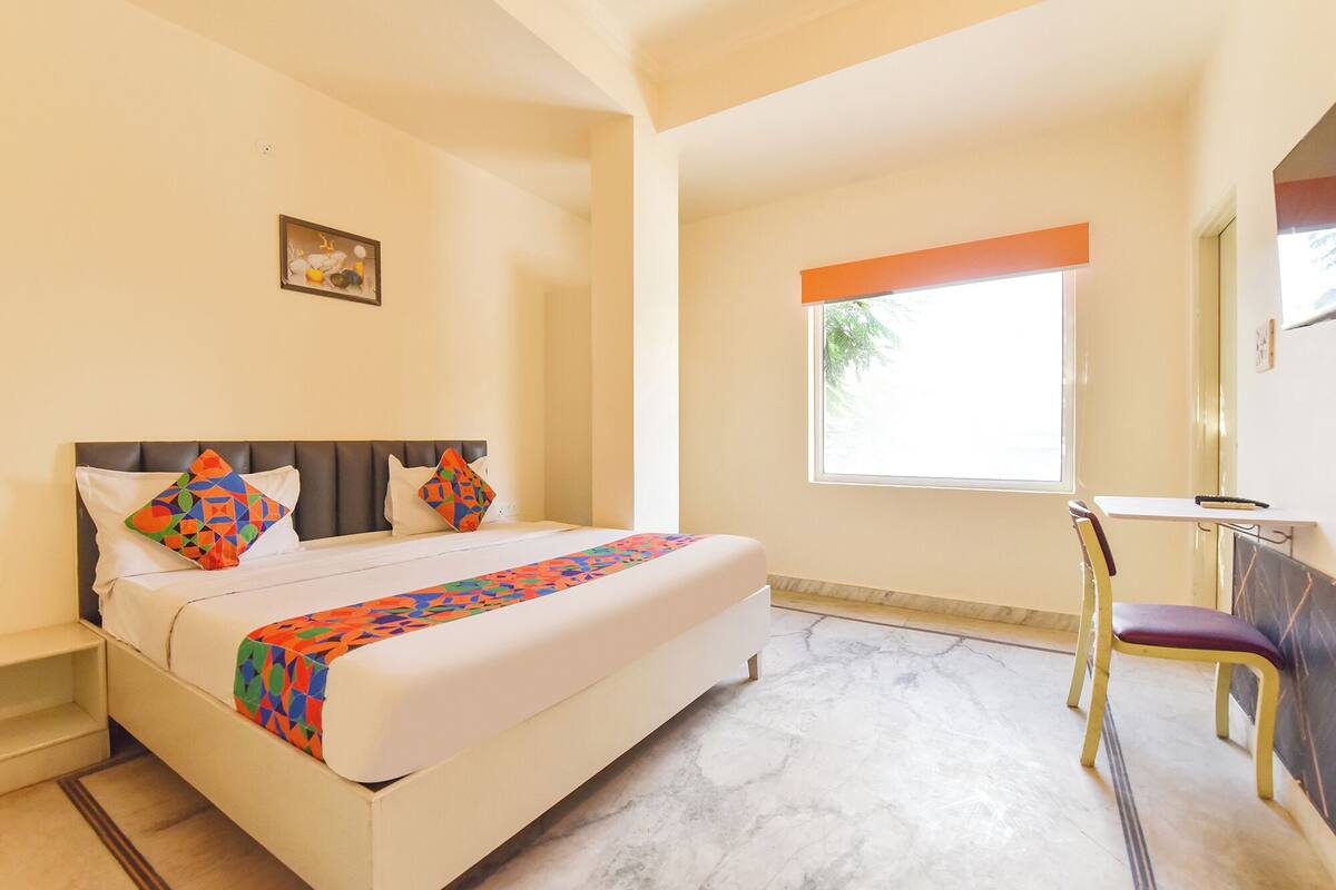 Ein Hotelzimmer mit Bett, Stuhl, Fenster und kleinem Schreibtisch.