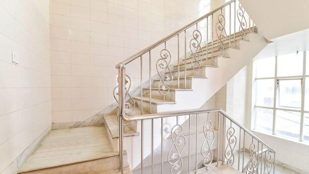 A staircase with ornate metal railings and marble steps in a well-lit interior space. - Fabhotel Mansarovar Retreat (Jaipur)