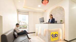 A hotel reception area with a receptionist, a waiting guest, and a reception desk. - Fabhotel Mansarovar Retreat (Jaipur)