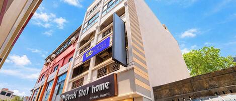 A hotel with a modern facade, balconies, and signage for 'Beach Stay Home.'