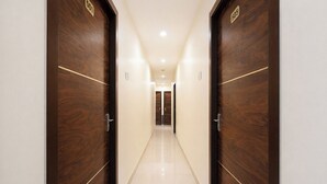A corridor with wooden doors, a tiled floor, and a light-colored wall.