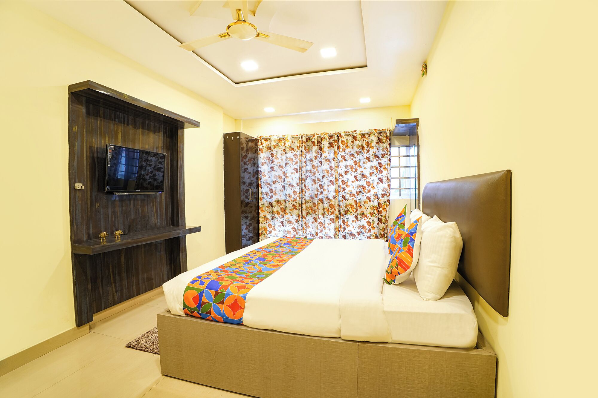 A bedroom with a bed, a television, a ceiling fan, and a shower curtain.