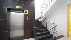 An elevator with a sign indicating 'LIFT FLOOR-4' and a staircase with a handrail.