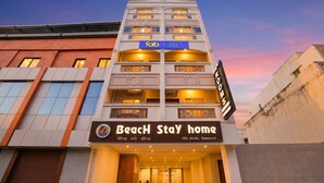 A multi-story building with a sign for 'Fab Hotels' and 'Beach Stay Home' hotel.