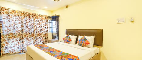 A bedroom with a bed, pillows, a headboard, a window with curtains, and a ceiling fan.