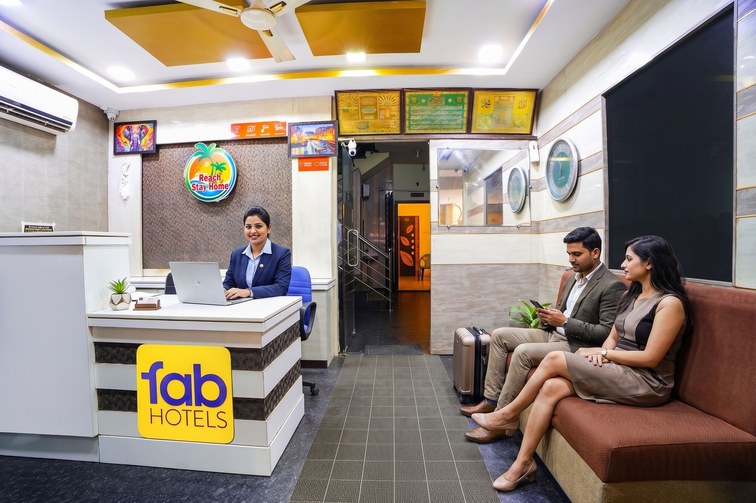 A reception desk with a laptop, a sign for 'fab hotels,' and a seating area with a couch and a person using a mobile device.