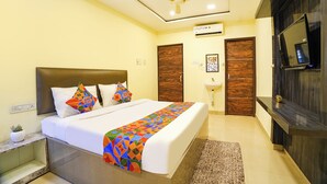A hotel room with a bed, a ceiling fan, a TV, and a wooden door.
