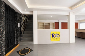 A hotel lobby with a staircase, a reception desk, and a sign for 'fab hotels'. - Fabhotel Fortune Inn (Pune)