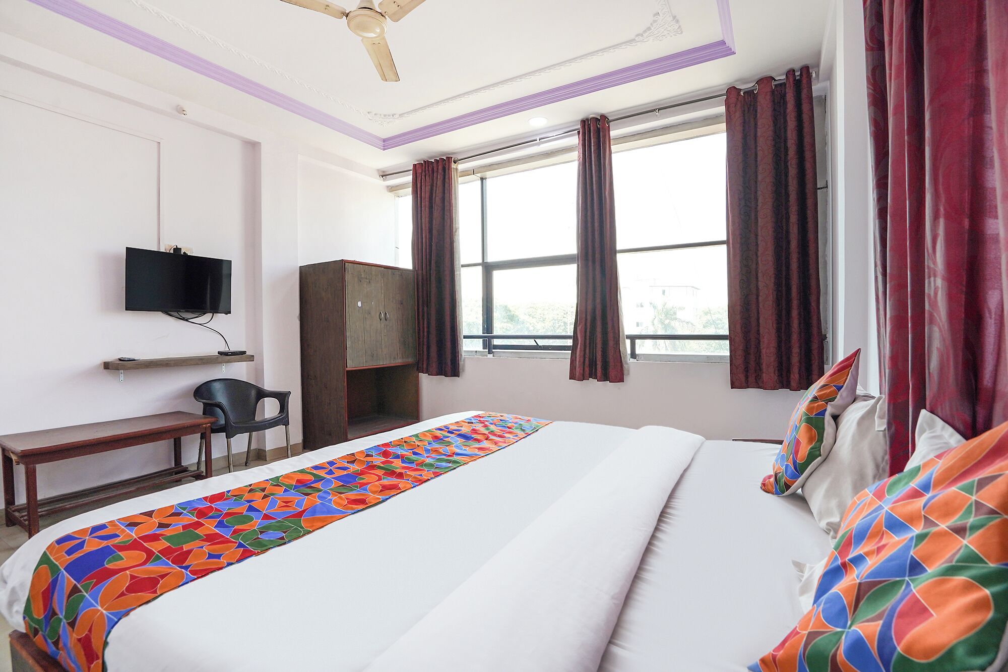 A hotel room with a bed, a desk, a television, and a wardrobe.