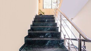 A staircase with a metal handrail, leading to a landing with a potted plant. - Fabhotel Shadowline (Panaji)