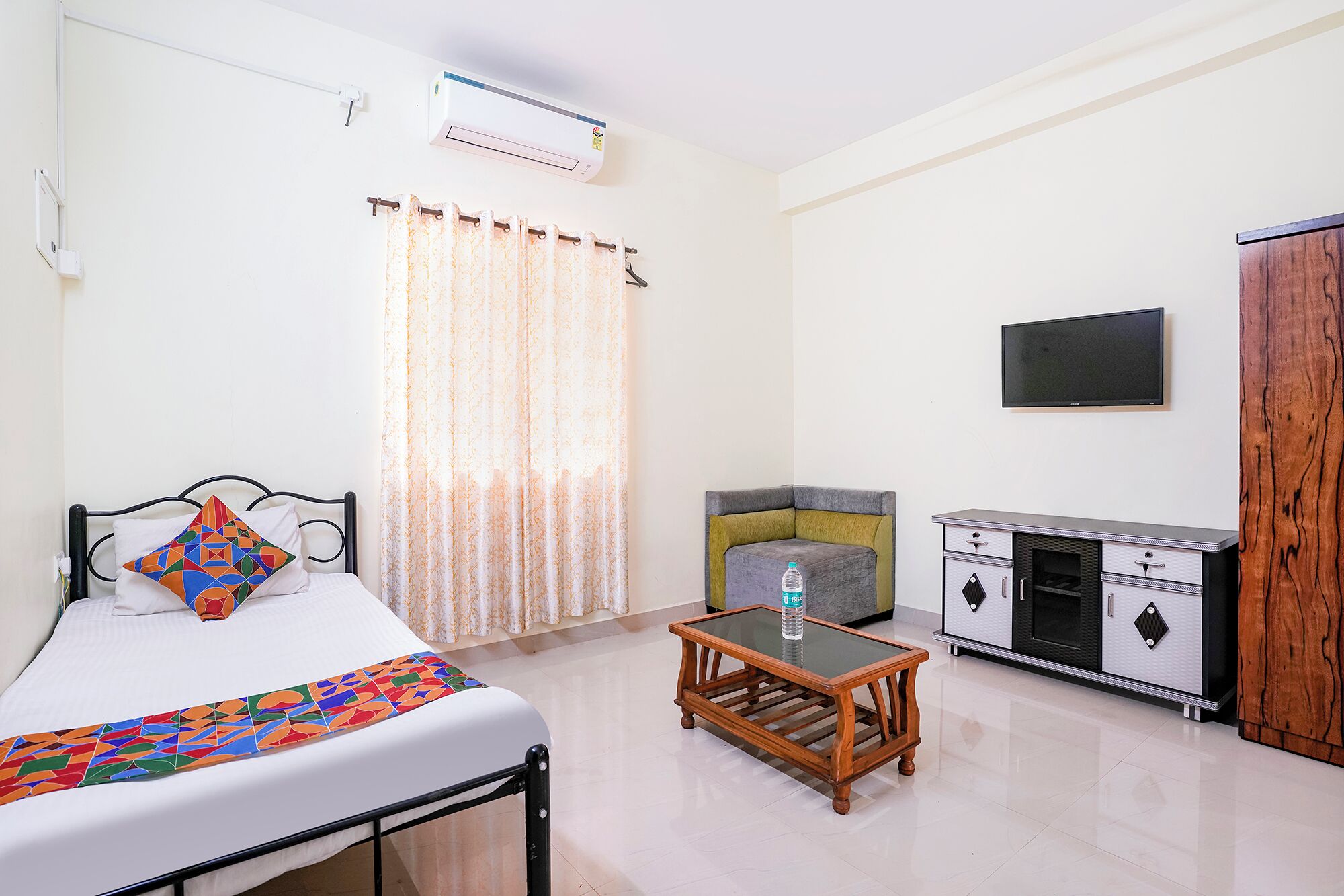 A hotel room with a bed, a small table, a TV, and a wardrobe.