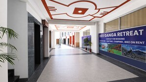 A hallway with a ceiling design, a sign for Dev Ganga Retreat, and potted plants. - Fabhotel Dev Ganga Retreat (Rishikesh)