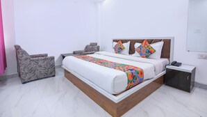 A modern bedroom with a large bed, a nightstand, a chair, and a mirror. - Fabhotel Dev Ganga Retreat (Rishikesh)
