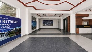 A hotel reception area with a modern design, including a reception desk, a hallway with a ceiling design, and two large posters advertising a retreat. - Fabhotel Dev Ganga Retreat (Rishikesh)