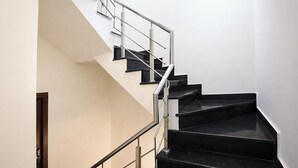 A staircase with black steps and a metal railing, leading to a landing. - Fabhotel Celebrity Inn (New Delhi)