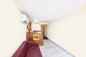 A reception desk with a 'fab hotels' sign, a red cushioned bench, and a tiled floor. - Fabhotel Celebrity Inn (New Delhi)