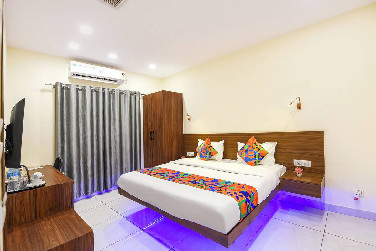 Une chambre d’hôtel équipée d’un lit, d’un bureau avec un ordinateur, d’un climatiseur et d’un rideau de douche.