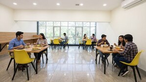 A dining area with multiple tables and chairs, large windows, and an air conditioning unit on the wall. - Fabhotel Celebrity Inn (New Delhi)