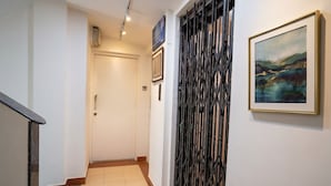 A hallway with a staircase, a door, a decorative metal partition, and a framed painting on the wall. - Fabhotel Krishna Sai (Pune)