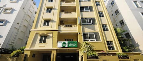 A multi-story hotel with a sign for 'fabHOTELS' at the top, a green sign indicating amenities like a conference hall and dine-in restrooms, and a modern architectural design.