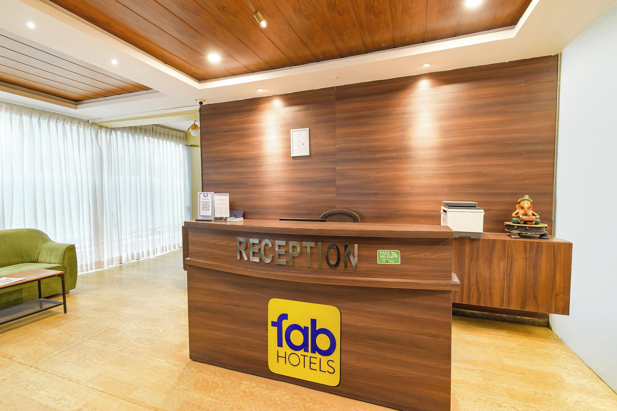 A reception desk with a wooden finish, a 'Reception' sign, a 'Free Wi-Fi' sign, and a 'fab hotels' logo.