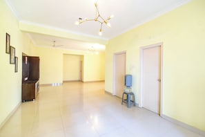 Um corredor espaçoso com piso de azulejos, ventilador de teto e bebedouro.