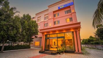 A hotel with a prominent sign, a glass facade, and a paved entrance area.