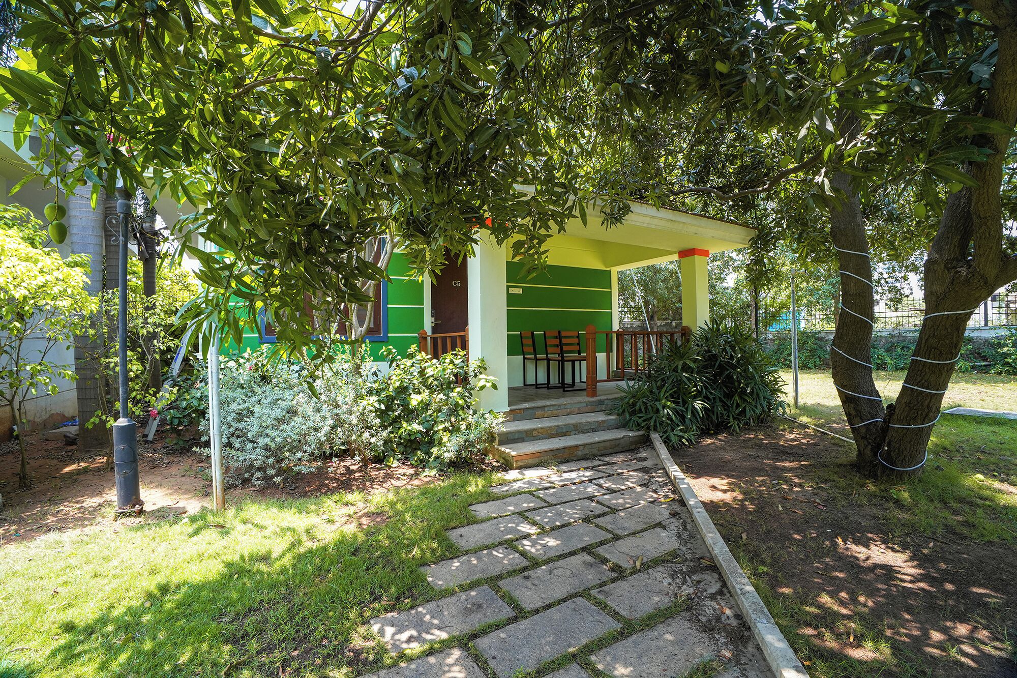 A covered outdoor seating area with steps leading up to a building with green and yellow walls.