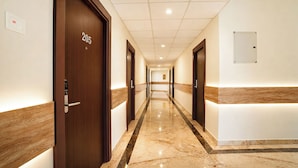 A hotel hallway with wooden doors, numbered 205, and a marble floor. - Fabhotel Grand & Resorts (Tirupporur)