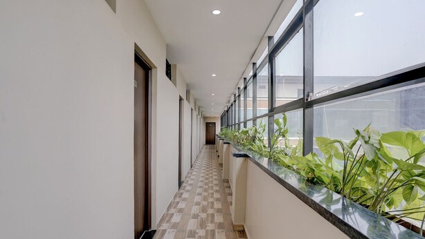 Un pasillo con piso a cuadros, ventanas grandes y una fila de plantas a lo largo de la pared.