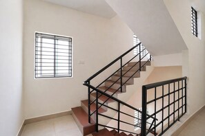A staircase with a metal railing, a window with bars, and a plain wall. - FabHotel MM Home Stay (Chennai)