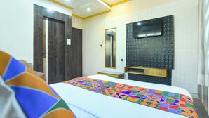 A hotel room with a bed, a TV mounted on the wall, and a door. - Fabhotel Guest O Polis Rajdanga (Kolkata)