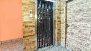A hallway with a wooden wall, a black metal gate, and a door with a stone-like texture. - Fabhotel Guest O Polis Rajdanga (Kolkata)